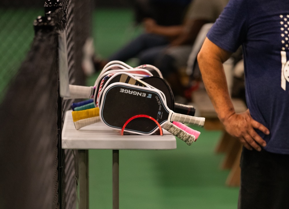Demo paddles stacked on a table beside the courts at Club13
