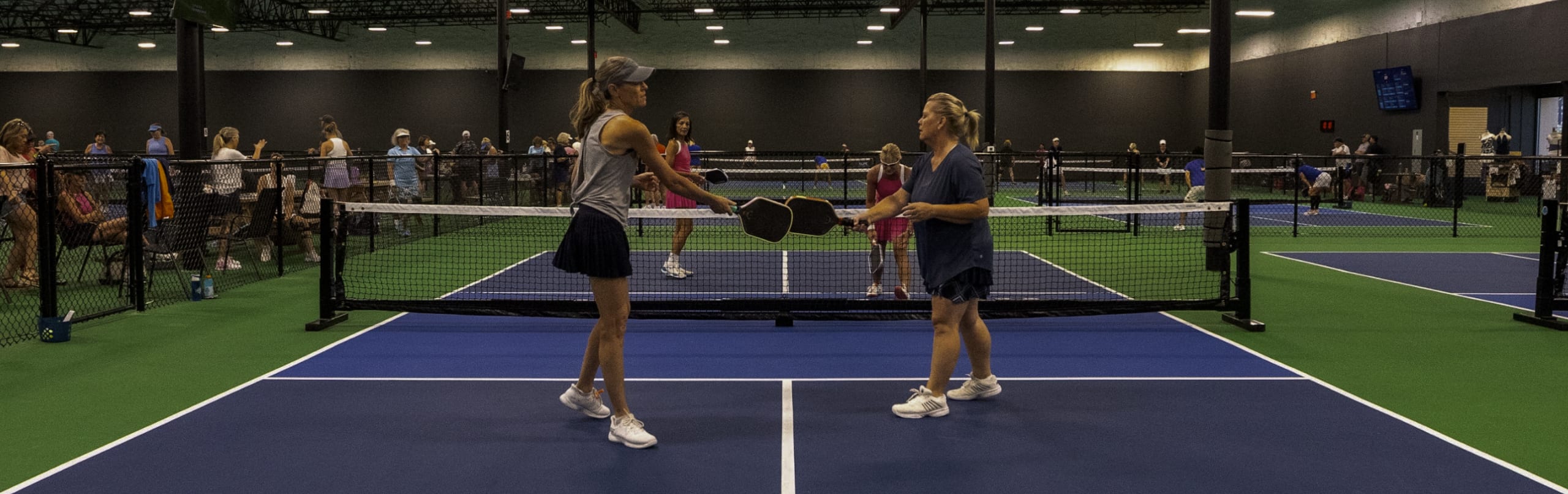 Players rallying at the net on the indoor courts