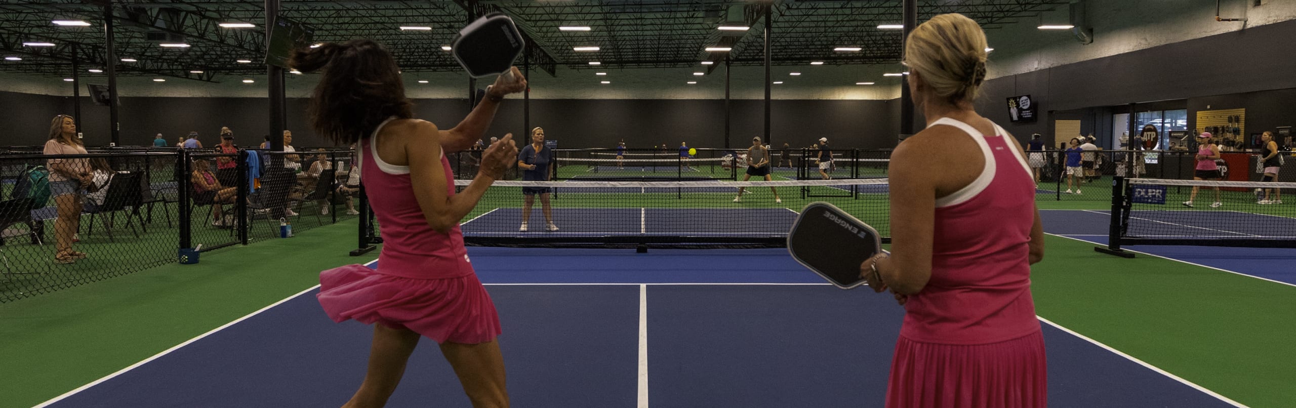 Doubles play across the indoor courts at Club13